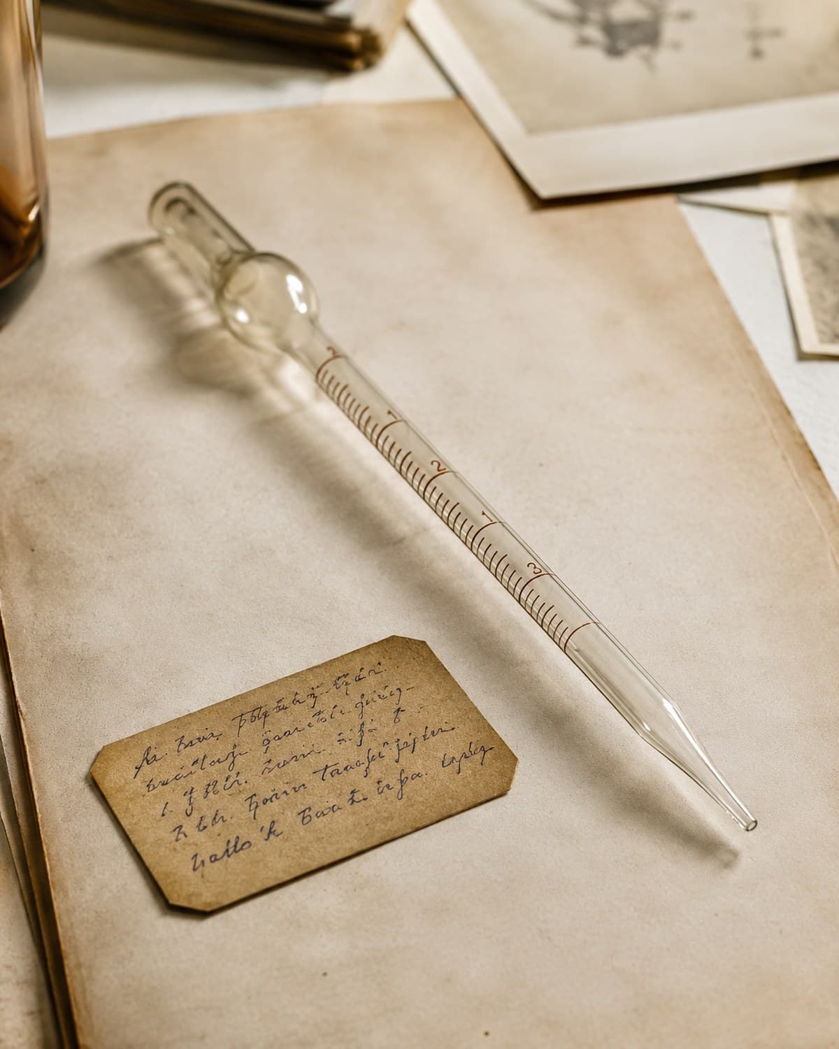 Pipeta de vidro Pasteur graduada sobre um caderno de laboratório envelhecido com uma etiqueta manuscrita — evoca o laboratório de Loren Pickart em 1973, quando o tripeptídeo GHK-Cu foi isolado pela primeira vez