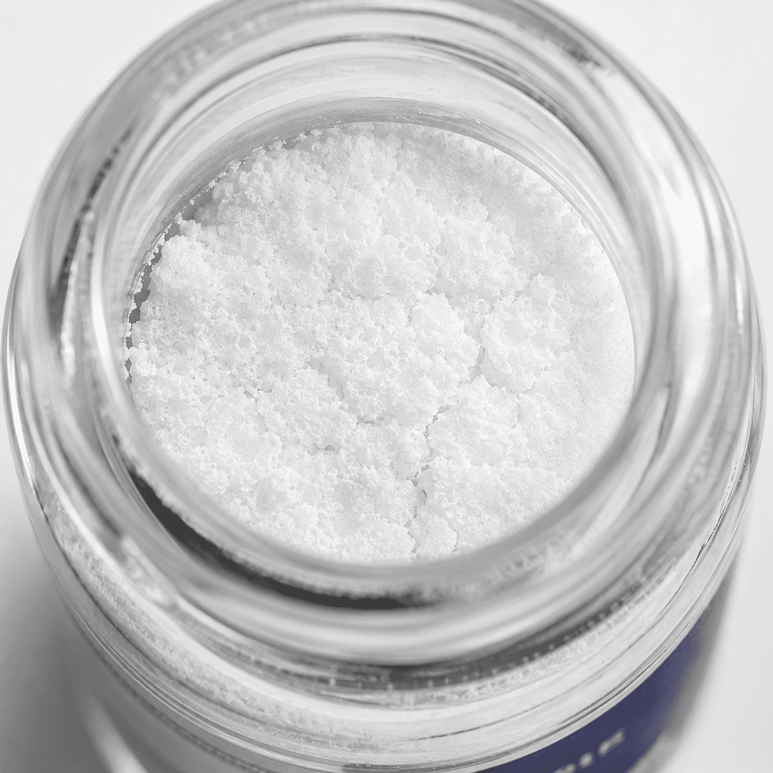 西林瓶内 retatrutide 白色冻干粉的微距摄影,在实验室冷调漫射光下呈现冻干饼多孔而均匀的质地。